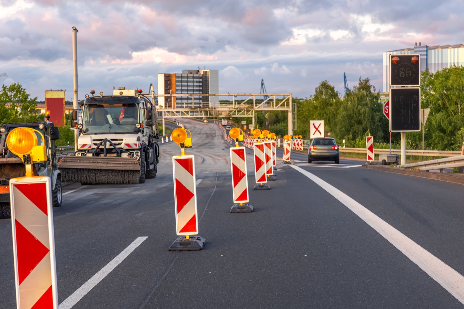 Road-works site with lane barriers and machinery on a highway at dusk