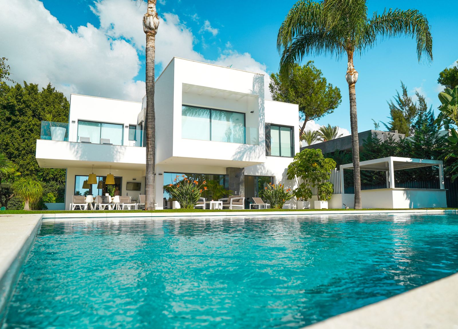 Modern white villa with a pool and palm trees under a blue sky in Dubai